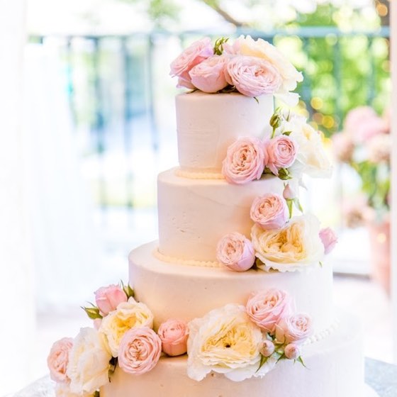 Une pièce montée à quatre étages, garnie de roses pâles